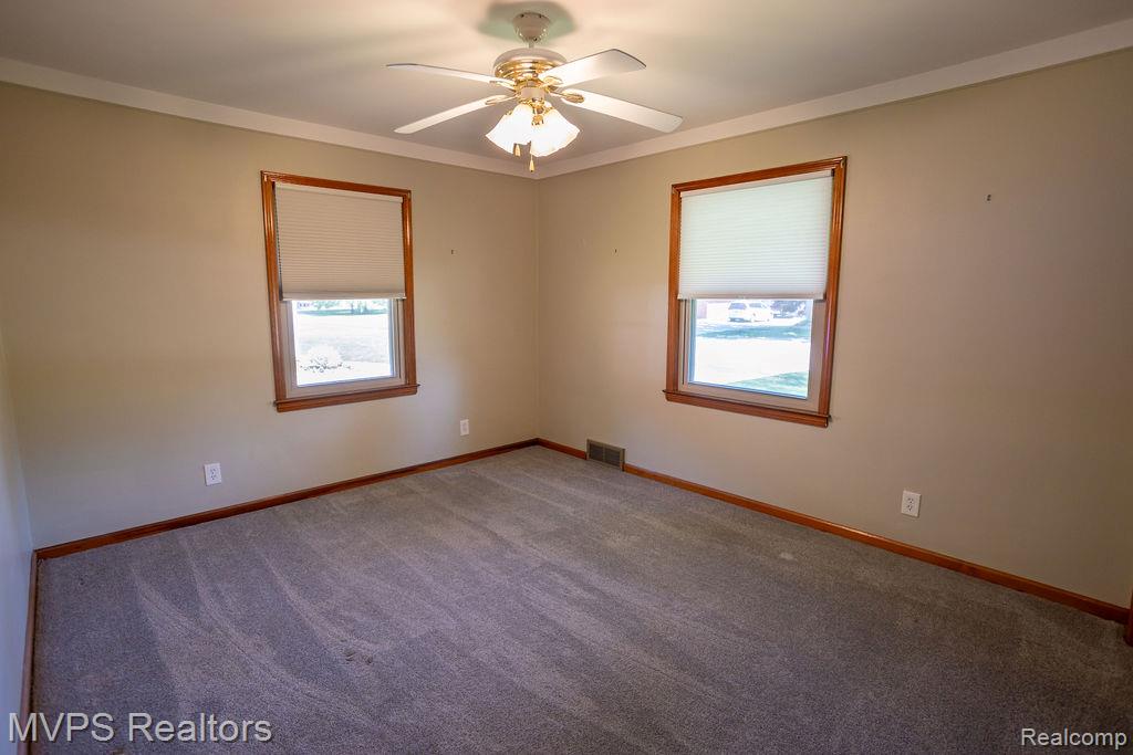 33033 Edgegrove Road Fraser, MI 48026 - Photo 12 of 20 Carpeted room featuring two windows with wood trim, a ceiling fan with light fixture, and crown molding
