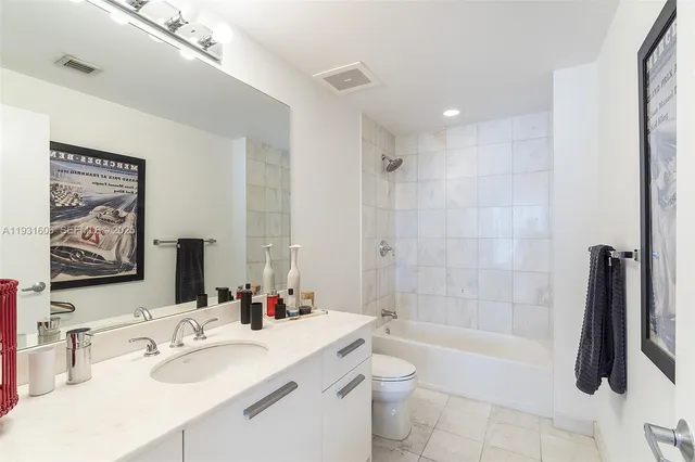 a bathroom with a sink a toilet a mirror a bathtub and shower