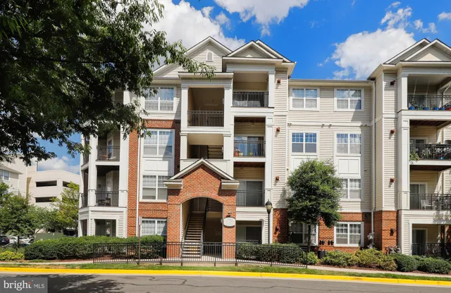 a front view of a residential apartment building with a yard and potted plants