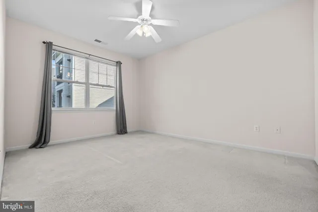 an empty room with chandelier fan and windows