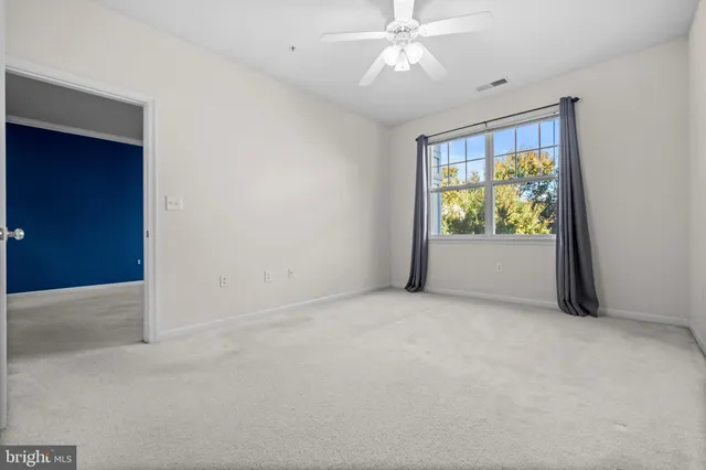 an empty room with windows and ceiling fan