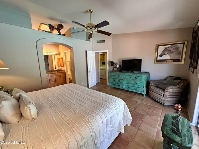 a bedroom with a bed mirror on dresser and a chandelier