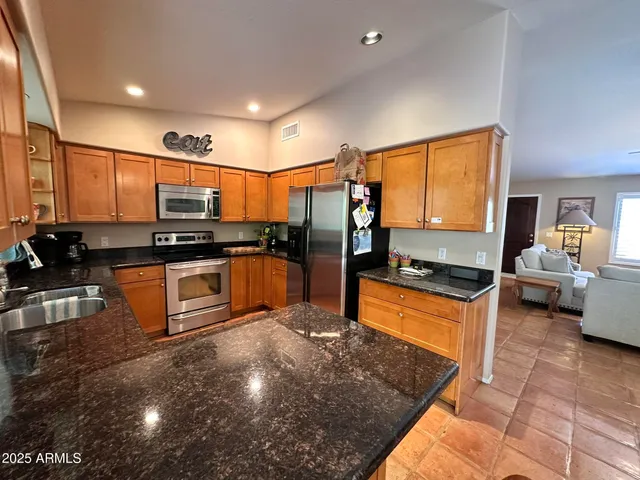 a kitchen with stainless steel appliances granite countertop a stove top oven a sink and a refrigerator