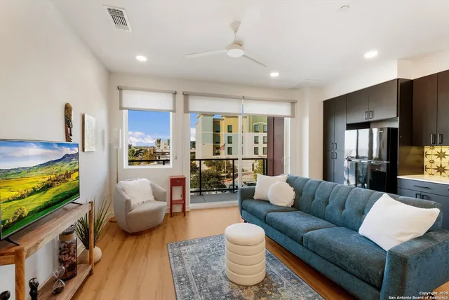 a living room with furniture kitchen view and a wooden floor