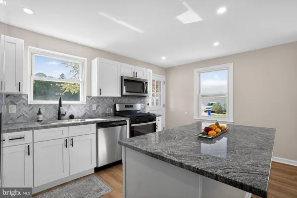 a kitchen with stainless steel appliances granite countertop a sink stove and cabinets