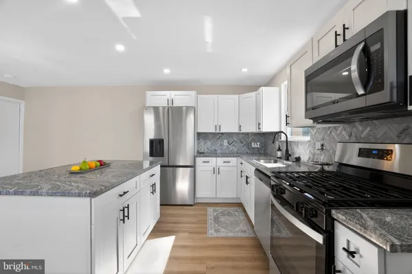 a kitchen with stainless steel appliances granite countertop a stove a sink and a microwave