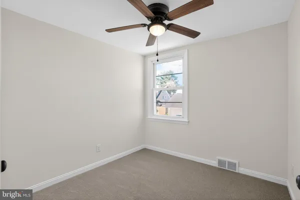 an empty room with a window and a fan