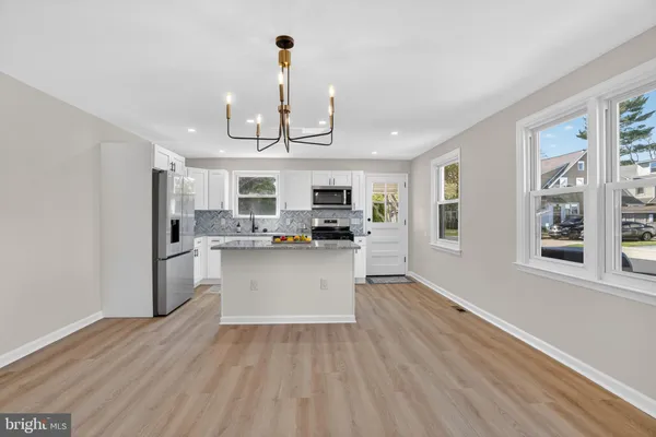 a view of a kitchen with center island wooden floor stainless steel appliances and cabinets