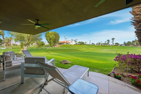 a view of a patio with table and chairs potted plants and a palm tree