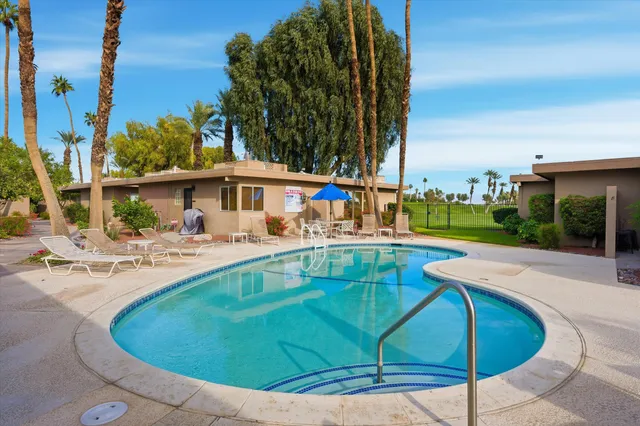 a view of backyard with swimming pool and seating space