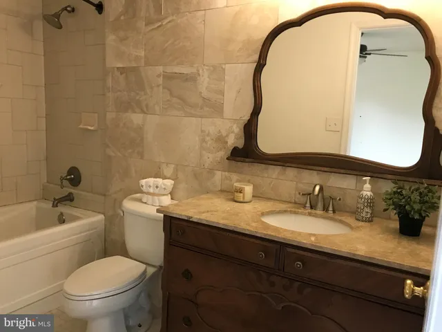 a bathroom with a granite countertop toilet a sink and a mirror
