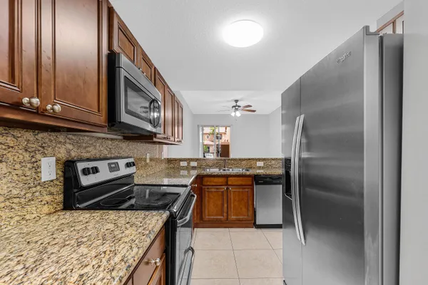 a kitchen with stainless steel appliances granite countertop a refrigerator a stove and a sink with wooden floor