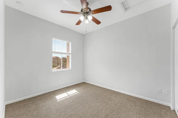 an empty room with a window and a ceiling fan