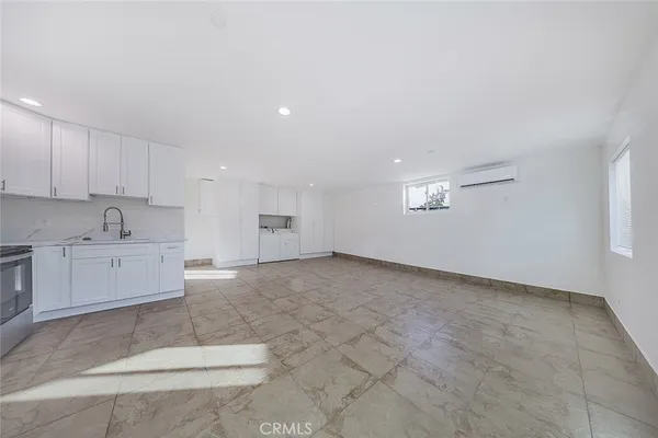 a large white kitchen with stainless steel appliances granite countertop a stove a sink a microwave and a refrigerator