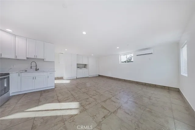 a large white kitchen with stainless steel appliances granite countertop a stove a sink a microwave and a refrigerator