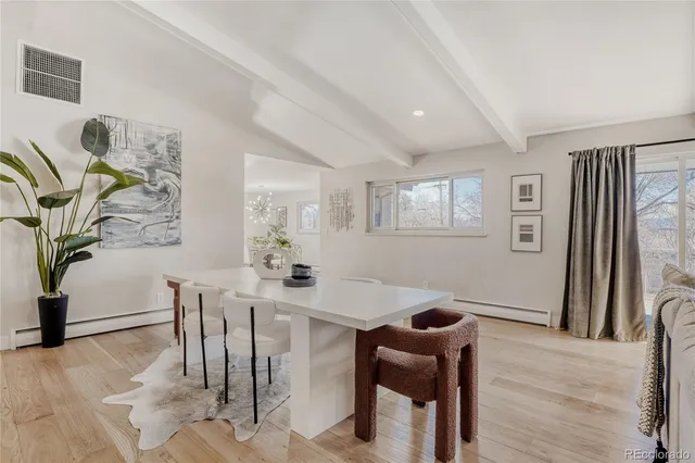 a kitchen with stainless steel appliances granite countertop a stove top oven a refrigerator a sink and a dining table with wooden floor