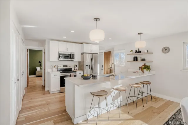 a kitchen with stainless steel appliances a sink a stove a dining table and chairs