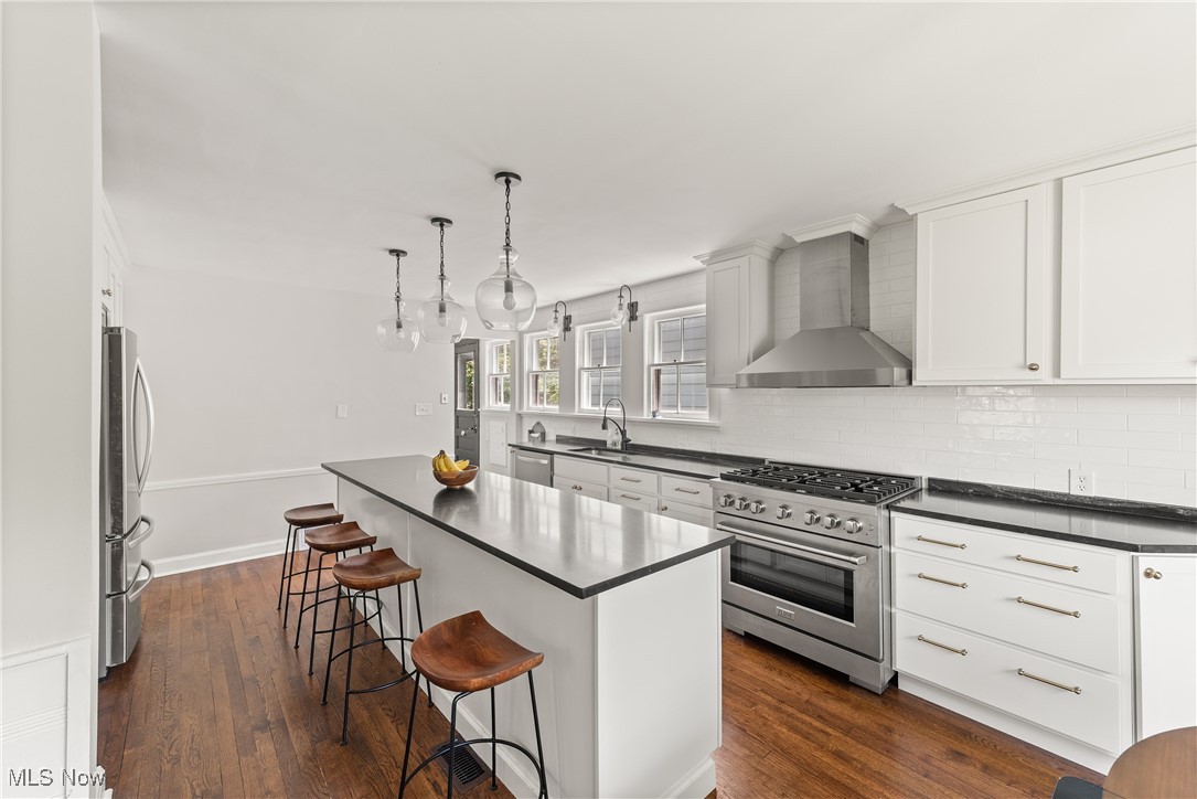 2464 Channing Road Cleveland, OH 44118 - Photo 12 of 44 Kitchen with stainless steel appliances, wall chimney exhaust hood, dark countertops, a center island, and tasteful backsplash