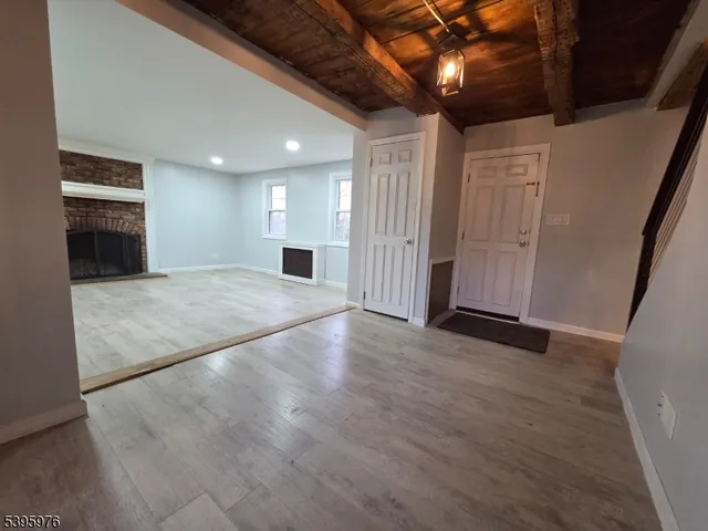 a view of an empty room with wooden floor and a kitchen