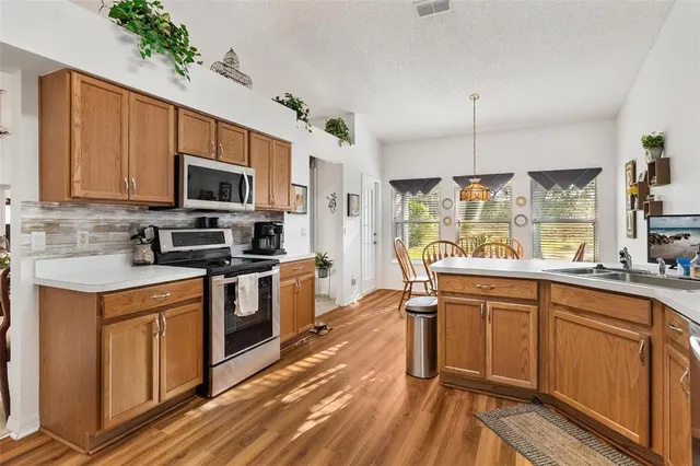 a kitchen with stainless steel appliances a sink a stove top oven a counter space and cabinets