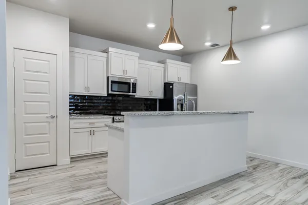 a kitchen with a refrigerator a stove and white cabinets with wooden floor