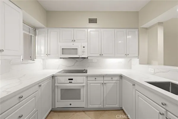 a kitchen with white cabinets and white appliances
