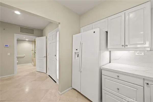 a view of a kitchen with refrigerator and white cabinets