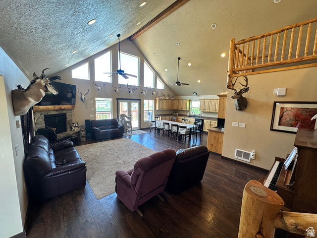 12 Crook Street Fish Haven, ID 83287 - Photo 14 of 35 Living room featuring a stone fireplace, dark wood finished floors, a ceiling fan, healthy amount of natural light, and a high textured ceiling