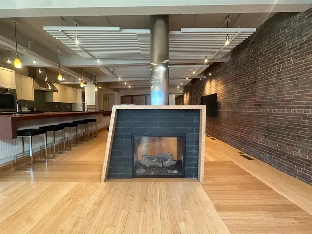 a living room with stainless steel appliances kitchen island furniture and a fireplace