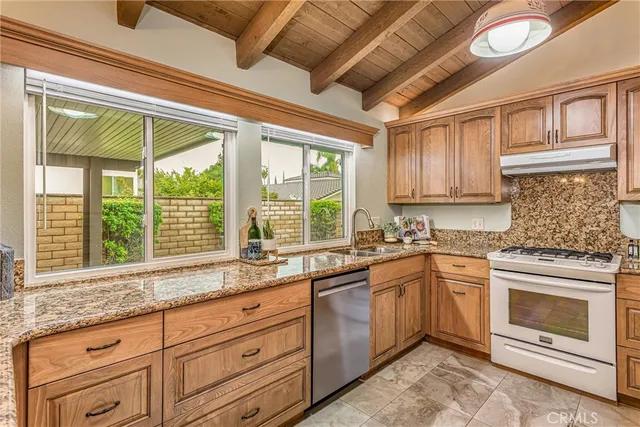 a kitchen with granite countertop stainless steel appliances sink stove and cabinets