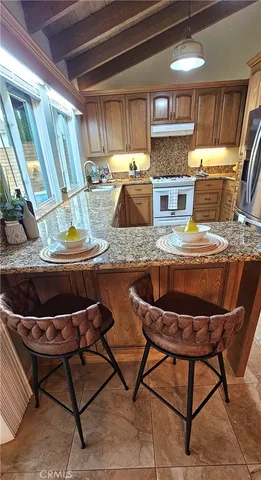 a kitchen with stainless steel appliances granite countertop table chairs sink and wooden cabinets