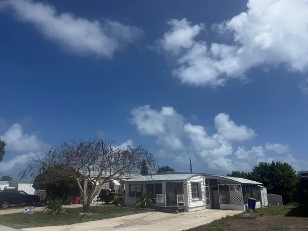 a view of a white house next to a yard