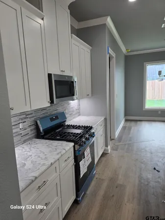 a kitchen with granite countertop a stove and a wooden floors