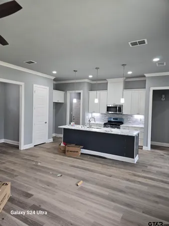 a large white kitchen with stainless steel appliances granite countertop a stove and a refrigerator