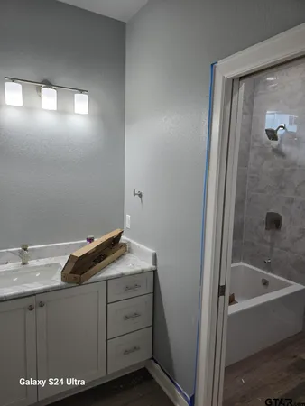 a bathroom with a granite countertop sink and a bathtub