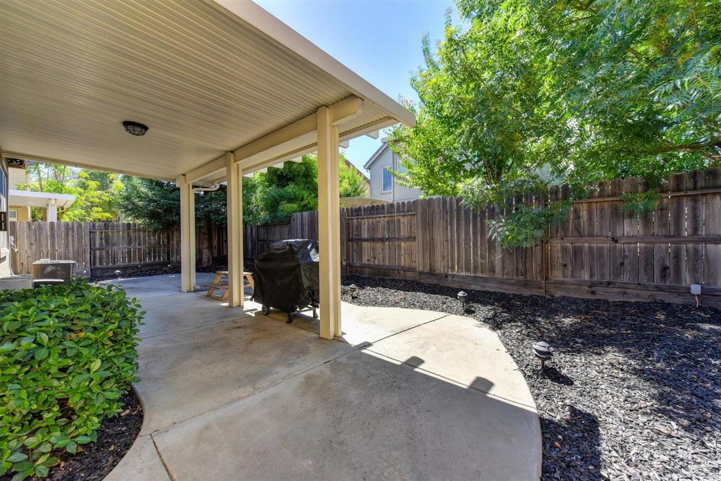 3557 Rainsong Circle Rancho Cordova, CA 95670 - Photo 26 of 27 a view of a backyard with wooden fence and a large tree
