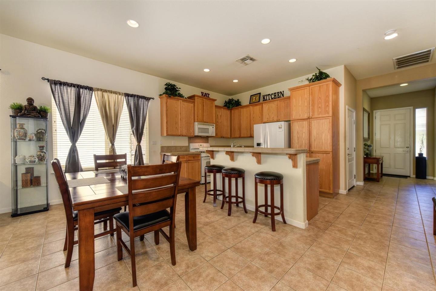 3557 Rainsong Circle Rancho Cordova, CA 95670 - Photo 10 of 27 a kitchen with kitchen island wooden cabinets and refrigerator