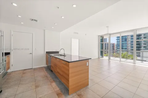 a large white kitchen with granite countertop a sink and white cabinets