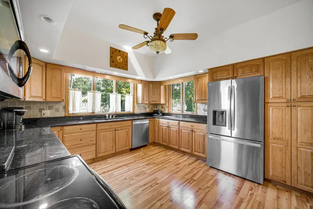 a kitchen with stainless steel appliances granite countertop a refrigerator a stove a sink dishwasher and a stove with wooden floor