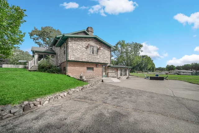 a view of a yard in front of a house with plants and large tree