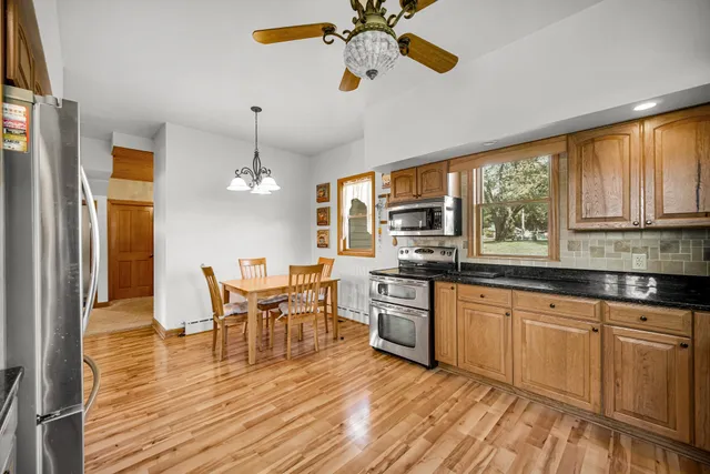 a kitchen with stainless steel appliances granite countertop a kitchen island hardwood floor sink stove dining table and chairs