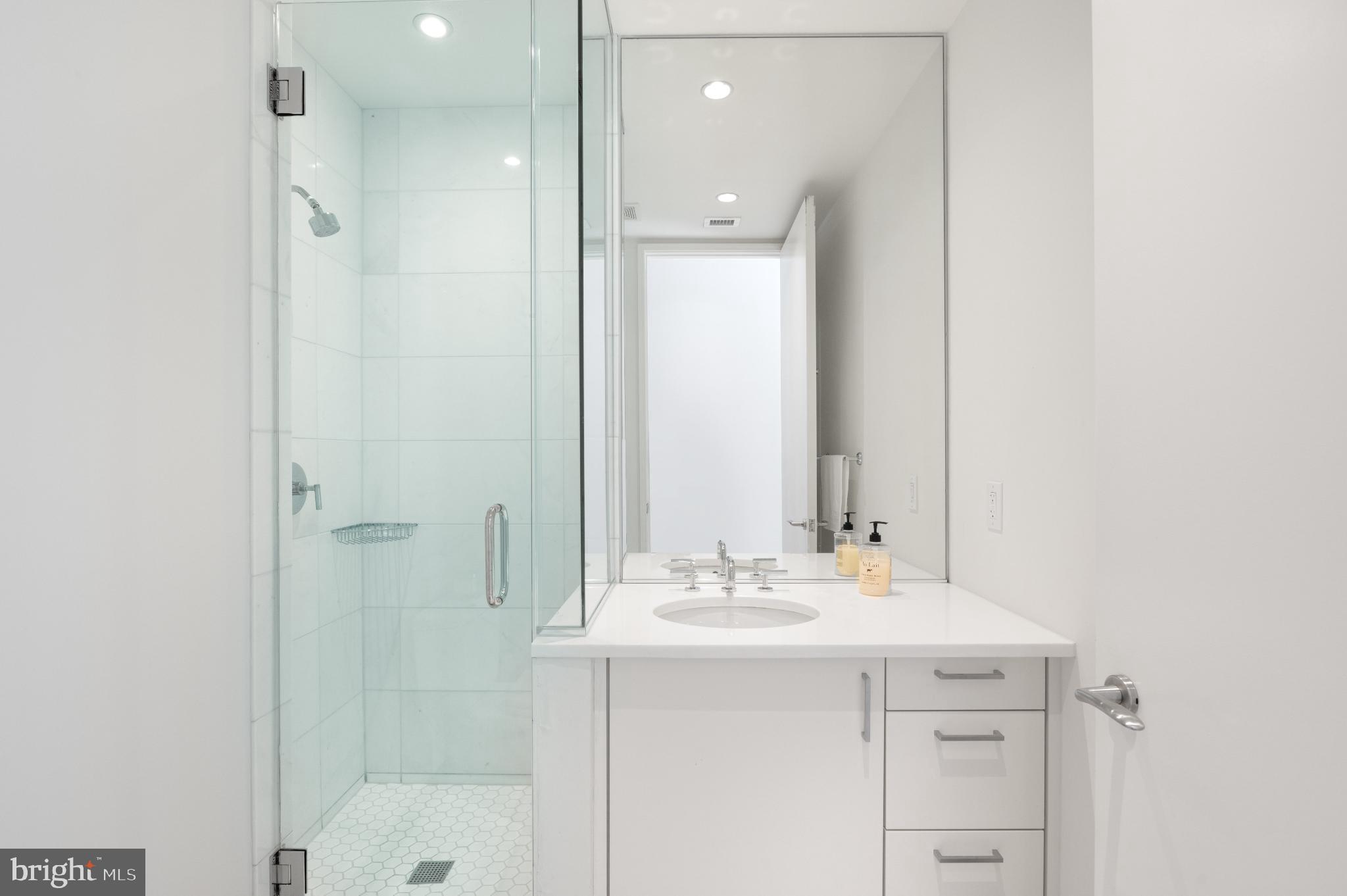 1177 22nd Street Northwest, Unit 2K Washington, DC 20037 - Photo 11 of 21 a bathroom with a shower sink vanity and mirror