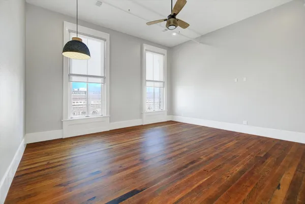 a view of a room with wooden floors ceiling fan and window