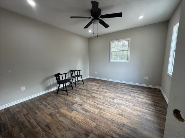 a view of an empty room and window and ceiling fan