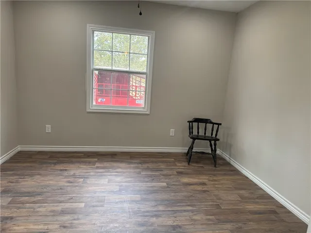 a view of an empty room with window and wooden floor
