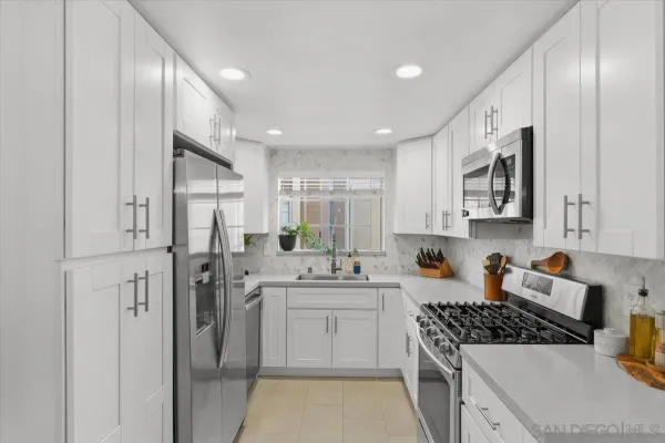 a kitchen with stainless steel appliances granite countertop white cabinets a window and a sink