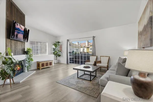 a view of a patio with couches and table and chairs with wooden floor and fence