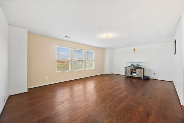 a view of an empty room with window and wooden floor