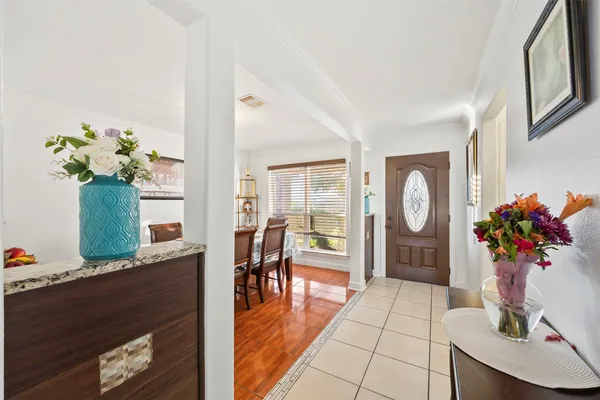a hallway with wooden floor and a vase of flowers