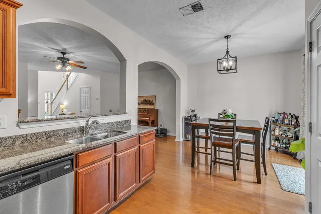 a dining room with stainless steel appliances granite countertop a table chairs and wooden floor